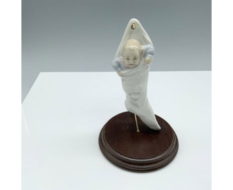 Glossy figure of a baby tucked into a Christmas stocking. Lladro backstamp. This item has a base included. 4" diameter circul