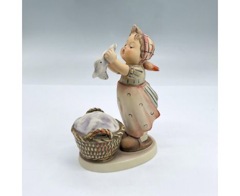 Hand painted figure of a girl in a headscarf and apron standing folding laundry with a basket at her feet. Goebel backstamp. 