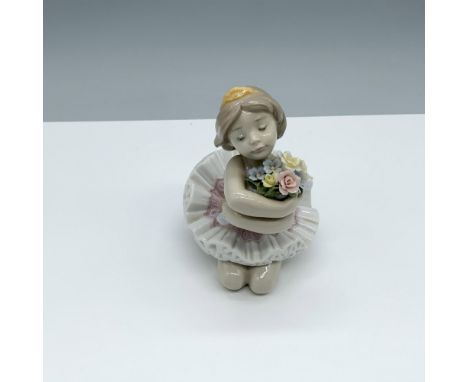Glossy figure of a young ballerina holding a bouquet of flowers. Lladro backstamp. This item has its original box 5.5"L x 4.7