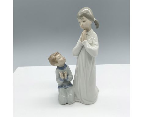 Glossy figure of a young girl teaching a young boy the proper way to pray. Lladro backstamp. This item has its original box. 