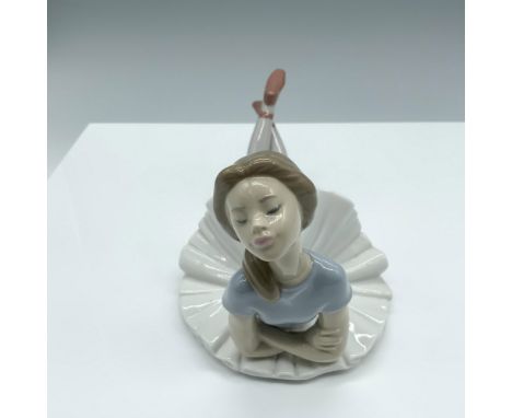 Glossy figure of a ballerina laying on the ground with her arms crossed. Lladro backstamp. This item has its original box. Bo