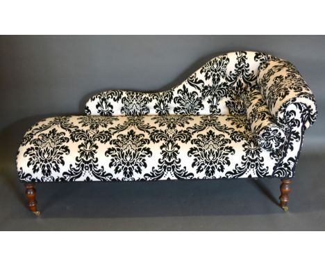 A 20th century small Chaise Lounge, with scroll end and button upholstery raised upon turned legs with brass casters, 144cms 