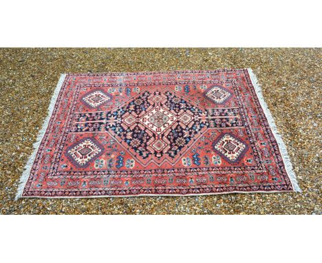A North West Persian woollen rug with a central medallion within an all over design upon a red, blue and cream ground within 