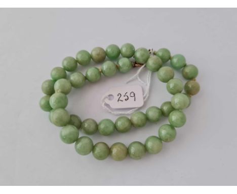 A Edwardian ungraduate jade bead necklace with gold clasp 16 inches