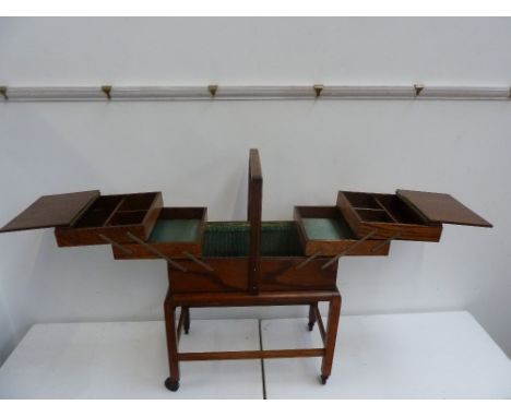A vintage cantilever sewing box on wheels  with various internal compartments 60cm h