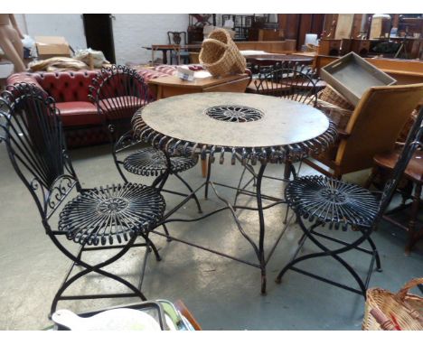 A vintage cast metal garden table with scrolling supports with four chairs ensuite