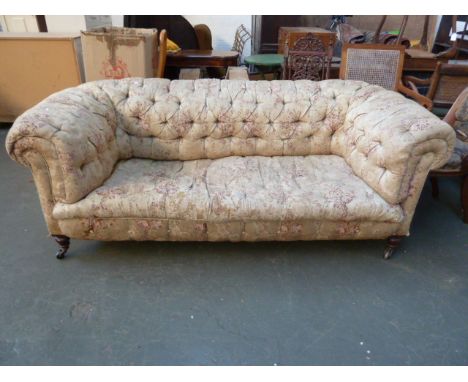 An early 20th century button back chesterfield style sofa, on turned legs and castors