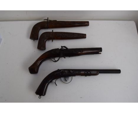 Two reproduction flintlock pistols, with two Indian daggers with pistolgrip handles, in carved wood scabbard