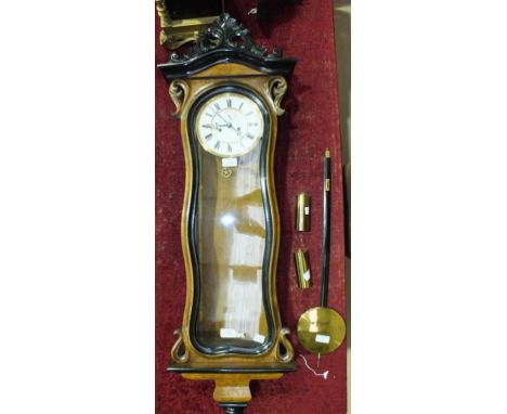A burr walnut, stained wood and ebonised Vienna-style wall clock, the serpentine-shaped glazed door enclosing a two-piece ena