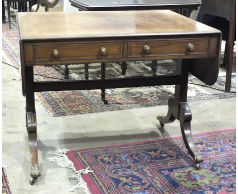 A Regency ebony-strung sofa table, the rectangular top with two drop leaves, above two cockbeaded drawers and corresponding f