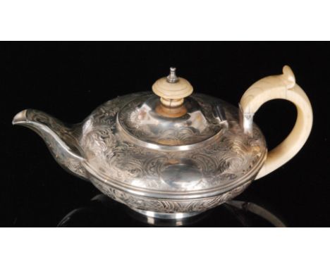 A George IV hallmarked silver melon shaped bachelors tea pot with foliate engraved decoration, ivory scroll handle and button