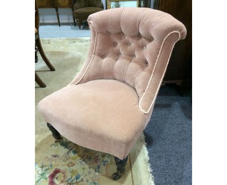 A late Victorian lady's chair with piped button down back over turned and tapered front legs, upholstered in pink draylon.