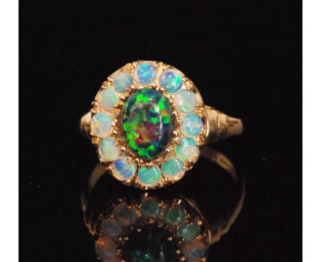 A 9ct hallmarked opal and synthetic black opal cluster ring, central synthetic opal within twelve stone opal surround, ring s