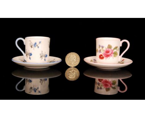 Two miniature Shelley coffee cans and saucers, one in blue and one in pink, both decorated with sprays of flowers, both with 