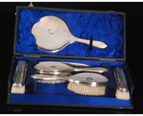 A cased hallmarked silver backed six piece brush set comprising four brushes, mirror and comb each with initial D within engi