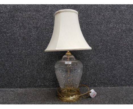 A glass table lamp with brass fittings and cream shade