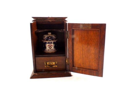 An Art Nouveau oak smokers cabinet with ceramic jar