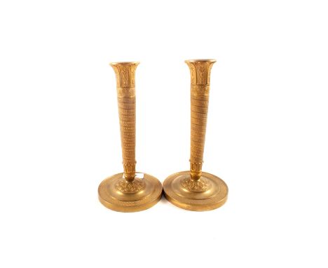 A pair of early 19th Century French gilt brass candlesticks with engine milled decoration to the tapering cylindrical columns