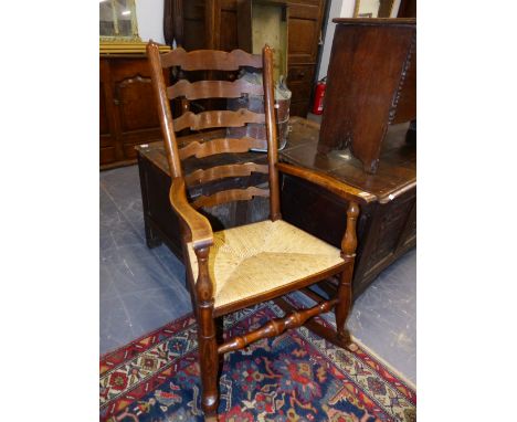 AN ANTIQUE ELM AND RUSH SEAT LADDER BACK ROCKING CHAIR.