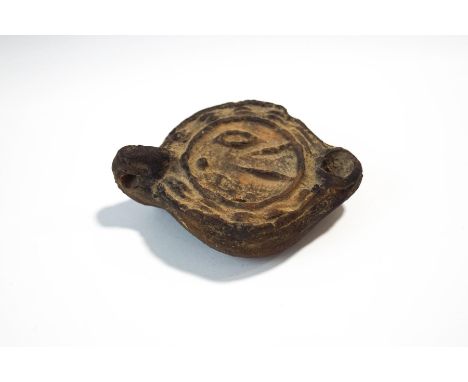 A Roman earthern ware oil lamp with moulded decoration, 11cm wide