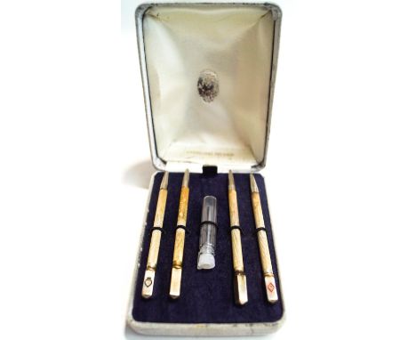 A set of four silver bridge pencils, with engine turned decoration and enamel terminals with a playing card suite, cased
