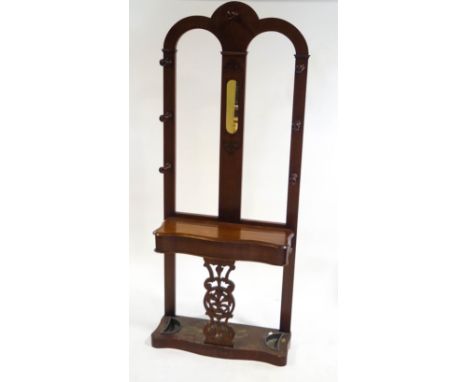 A Victorian mahogany hall stand with turned coat finials flanking a mirror above, a lift up shelf, above a carved and pierced