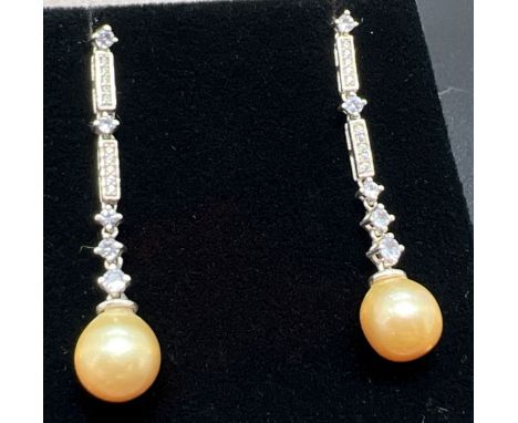 A pair of silver and dark cream pearl drop style earrings each set with 5 small round cut tanzanite stones and 10 small round