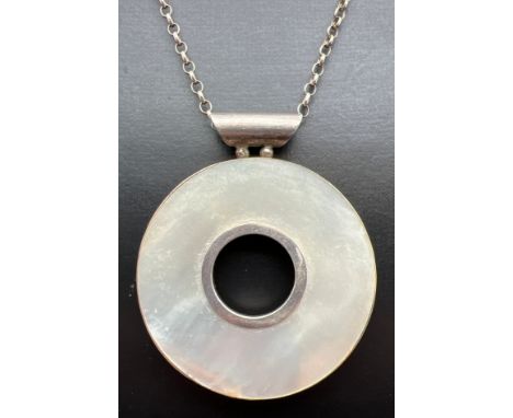 A large silver circular shaped pendant set with Mother Of Pearl, on a 24" belcher chain with spring ring clasp. Silver marks 