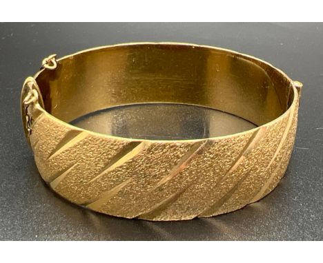 A vintage 9ct rolled gold bangle with brushed effect and diamond cut pattern. Marks to inside of bangle. Safety chain missing