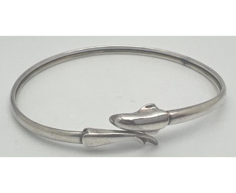 An adjustable silver bangle with dolphin detail. Marked Silver to inside. Approx. 7cm diameter. Total weight approx. 8g. 