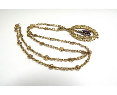 An ornate gold laurel leaf pendant, diamond set with diamond and ruby swinging drop, engraved "To Eva from Mam and Dad Aug 26