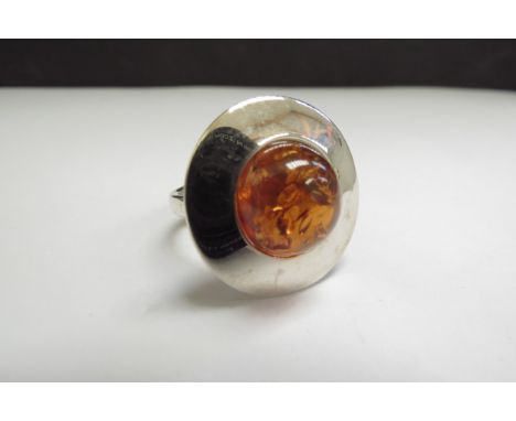 An amber dress ring of circular form, adjustable shank stamped 925. Size R+, 9.4g 