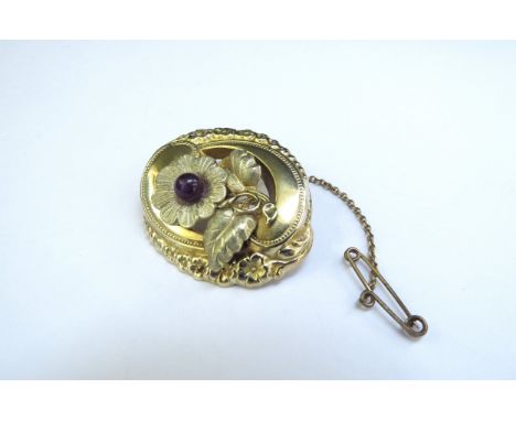 An unmarked gold brooch the centre as a flower with central amethyst in ornate frame with floral decoration, 8.5g 