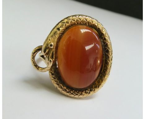 A gold ring with an oval cabochon cornelian in a snake surround, stamped 9ct. Size Q/R, 8.3g 