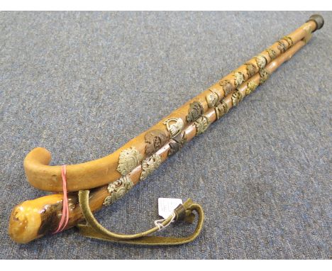 Cap badges: Two walking sticks decorated with brass and white metal cap badges. A traditional curved handle stick with 12 bad