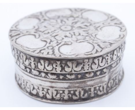 A late 17th Century white metal patch box, of drum form with slip lid, the latter relief decorated in depiction of a flowerhe