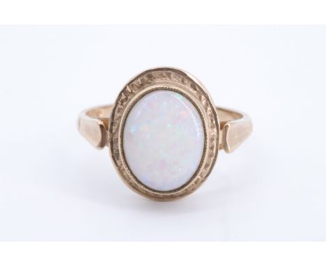 An oval opal cabochon ring, the stone of approx 10 mm x 8 mm bezel set between the fluted shoulders of a 9 ct gold shank, Q/R