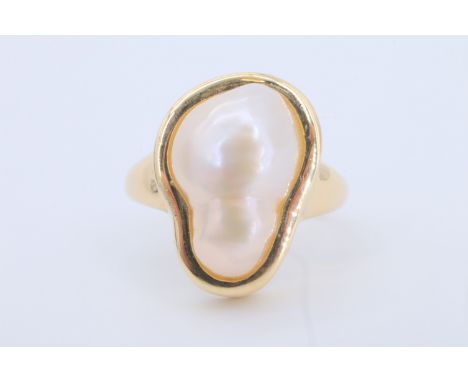 A baroque pearl finger ring, the pearl of approx 15 mm x 10 mm bezel set on a tapering 14 ct gold shank, 5.6 g