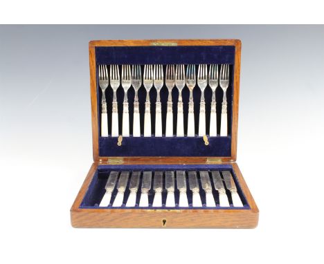 An Edwardian oak cased set of electroplate and mother of pearl fruit knives and forks, 12 settings, case having vacant escutc
