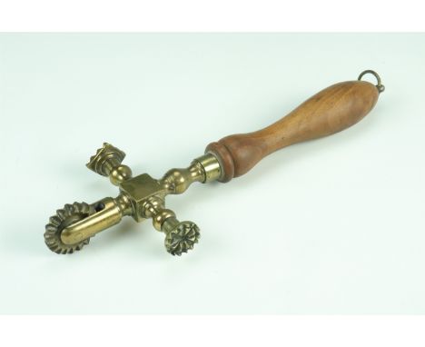 A 19th Century brass cruciform pastry jigger, with wheel lozenge form and circular prints, 30 cm 