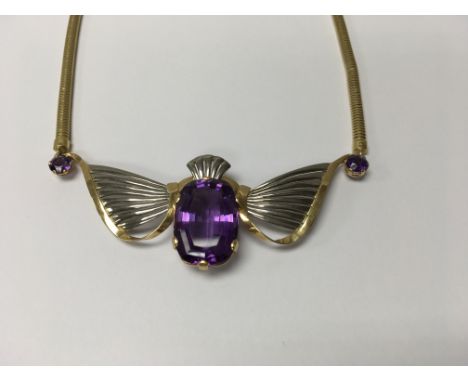 An Art Deco style unmarked gold necklace inset with large central amethyst flanked by stylised wings And two other small amet
