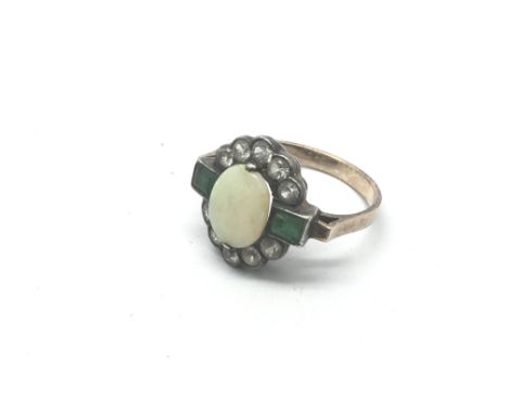An Art Deco design ring set with a central opal flanked by emeralds and CZs, unmarked, approx size J-K.