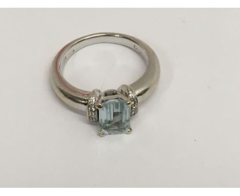 A 18 ct gold ring inset with central aquamarine flanked by diamonds size N .