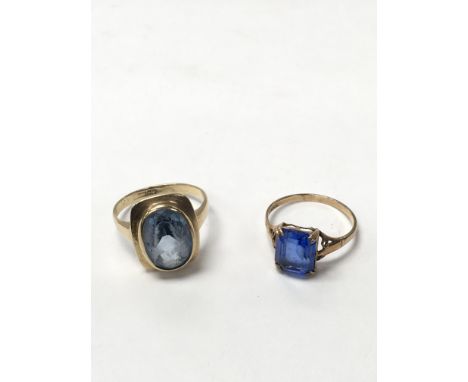 Two blue stone set rings. The square stone ring is approximately size M and weighs approximately 1.8g. The circular stone rin