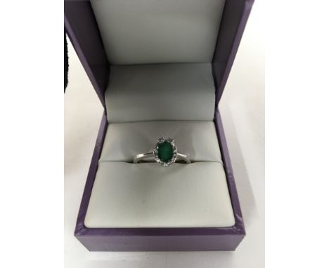 A 18 ct white gold ring with central emerald surround by diamonds.