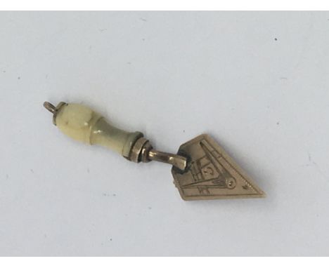 A 9ct gold trowel charm with a Masonic emblem.