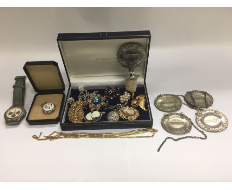 A small collection of costume jewellery, four spirit labels and a decanter stopper.