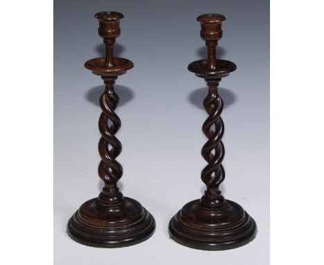 A pair of oak open-twist table candlesticks, campana sconces, dished drip pans, turned bases, 34.5cm high, early 20th century