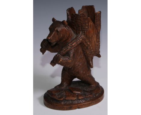 A Black Forest novelty spill holder, carved as a bear carrying a hollowed section of tree trunk, 24cm high, c.1900 