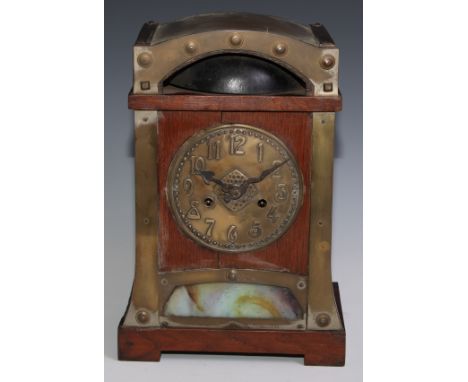 An Arts and Crafts oak mantel clock, repousse embossed brass dial with Arabic numerals, twin winding holes, the movement stri